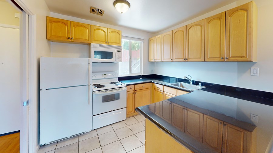 A kitchen with wooden cabinets and a black countertop.